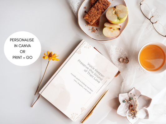 Image of the Voice keeper journal set on a table with a drink and snacks, a pen and reading glasses. 